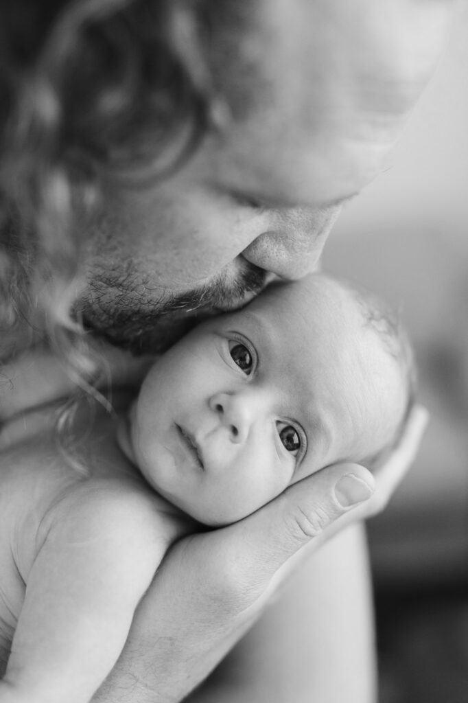 6 week old newborn being held in dads arms at a in home newborn session Perth