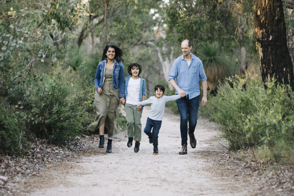 Family walking hand in hand along a bush track during a natural family photography session at Hovea Falls in Perth.