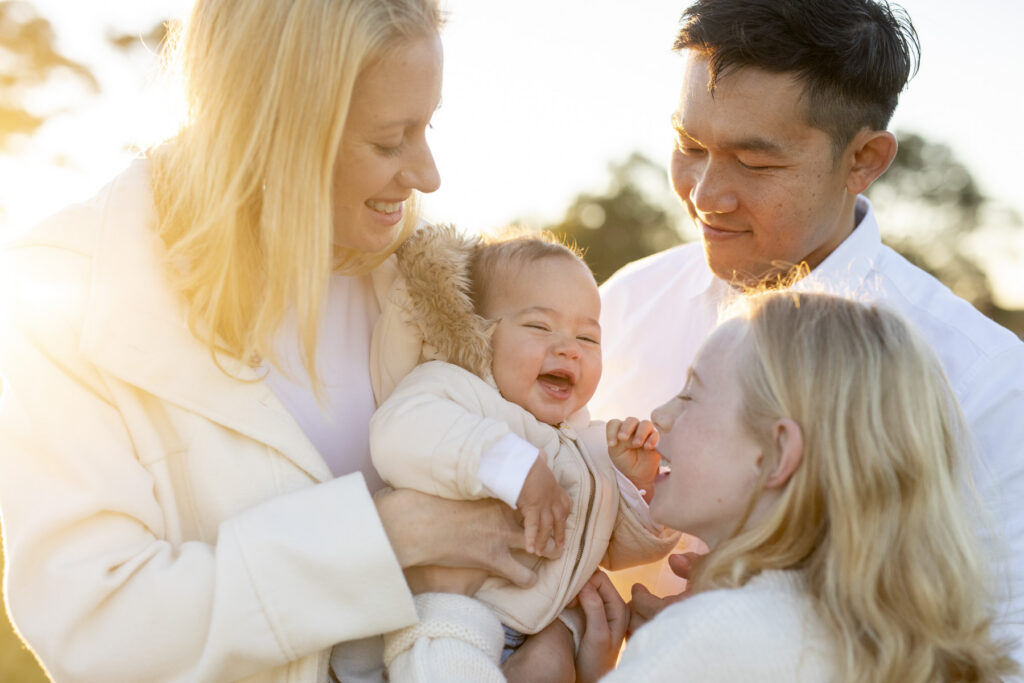 Smiling family with a happy baby enjoying a golden hour family photography session at Perry's Paddock, Floreat, Perth.