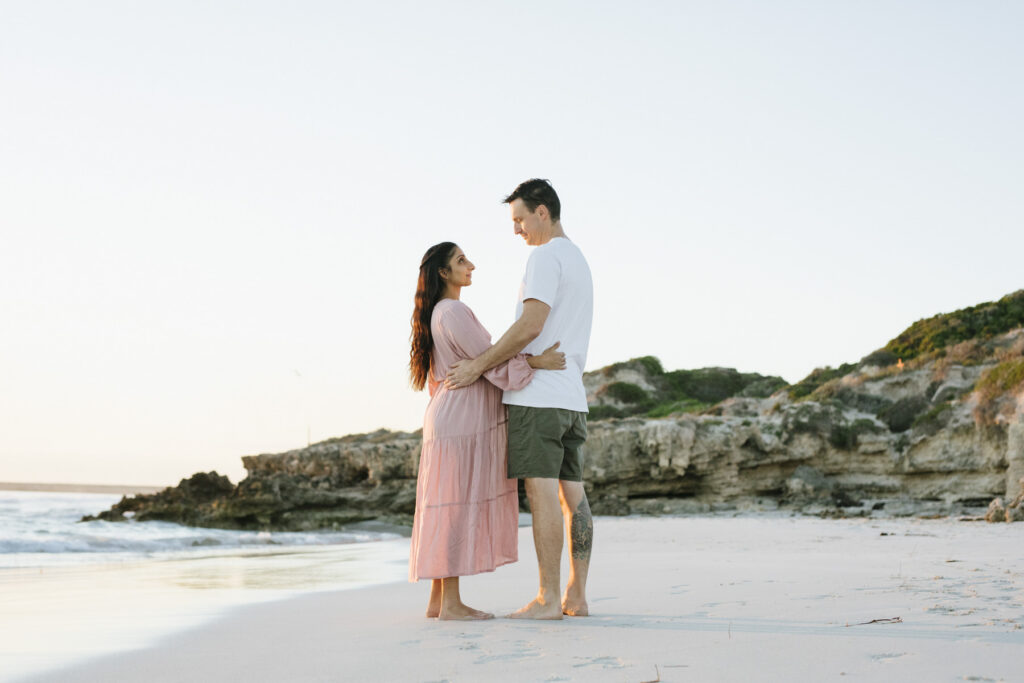 Expectant couple embracing on the beach at sunset during a maternity photography session at Mullaloo Beach, Perth.