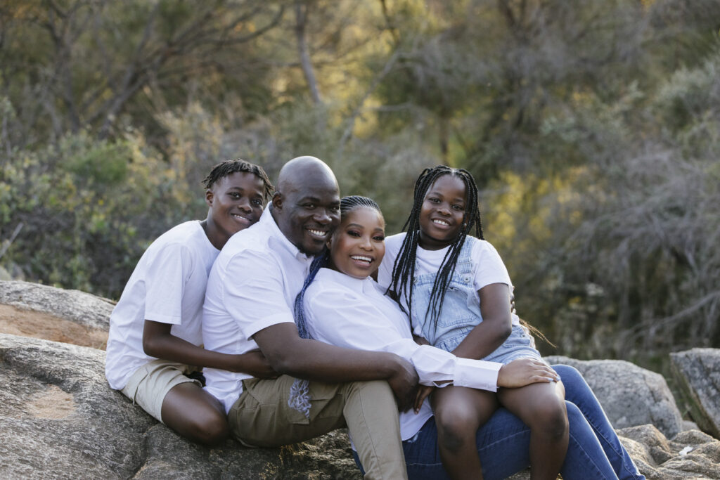 Family sitting together on granite rocks during a natural family photography session at Lesmurdie Falls in the Perth Hills.